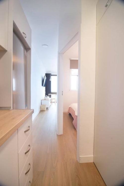 Heller moderner Flur in einer Wohnung in Santa Cruz de Tenerife mit weißen Wänden, Holzböden und Küchenspeicher.