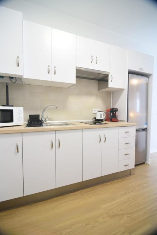 Moderne weiße Küche mit Holzarbeitsplatten, Edelstahlgeräten und Schränken in der Ferienwohnung Bahía Anaga
