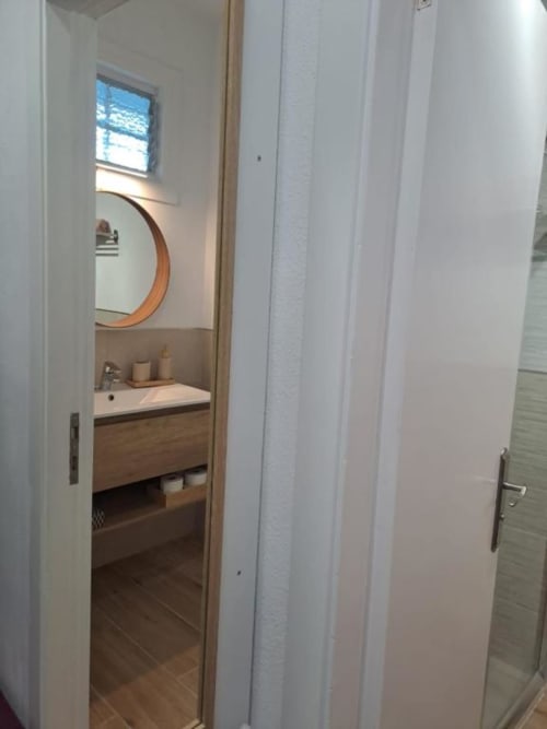 Modernes Badezimmer in der Bahía Anaga 703 Wohnung, Santa Cruz de Tenerife, mit Holzwaschtisch, rundem Spiegel und Tageslicht