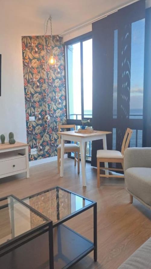 Modernes Apartment mit Meerblick auf Tenerife, Holzmöbel, farbenfrohe Wandteppiche und Balkonaussicht aufs Meer