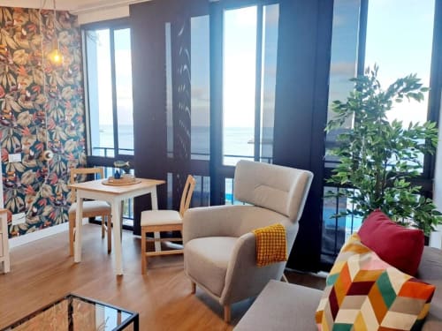 Modernes Wohnzimmer mit Meerblick-Balkon, beigem Sessel und Blumentapete auf Teneriffa