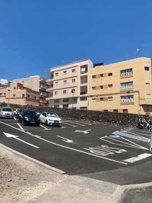Parkplatz mit drei Autos vor gelbem und beigem Apartmenthaus in Santa Cruz de Tenerife, Spanien