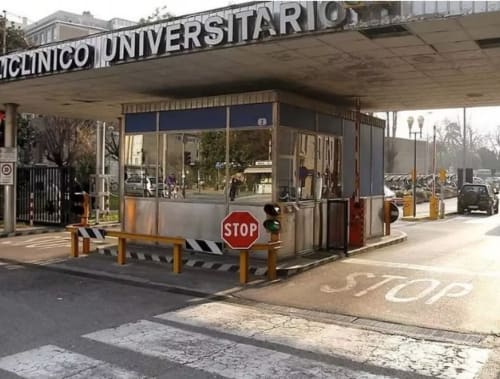 Entrance to Clinico Universitario medical facility in Padova with stop sign and security gate