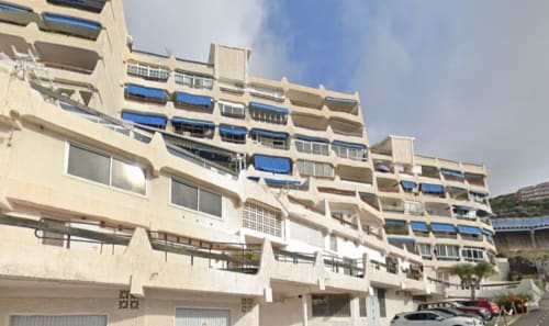 Beige apartment building with blue balconies in Santa Cruz de Tenerife, Canary Islands, featuring modern tiered architecture