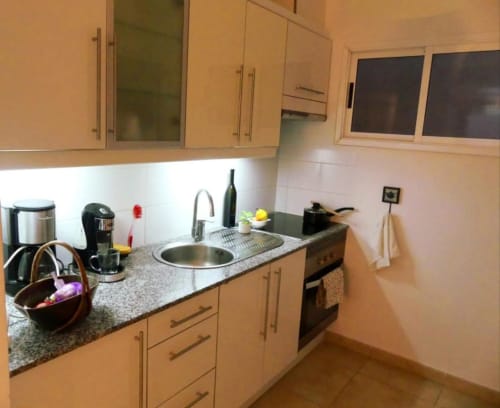Modern kitchen in Tabaiba Ocean View apartment in Santa Cruz de Tenerife with light wood cabinets, granite countertop, and