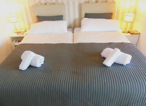 Two rolled white towels on dark bedspread in modern apartment bedroom at Tabaiba Ocean View, Santa Cruz de Tenerife
