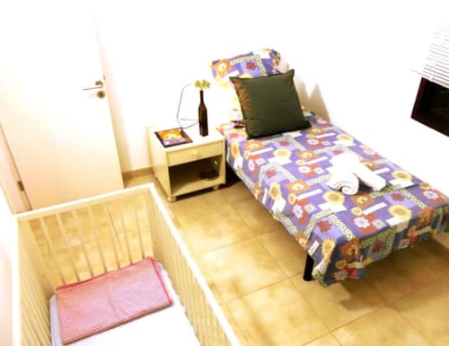 Bright bedroom in Tabaiba Ocean View apartment, Santa Cruz de Tenerife, with colorful bedding, wooden nightstand, and crib