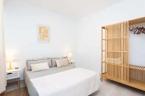 Modernes Schlafzimmer im Vive La Vacacional Renting auf Teneriffa mit Doppelbett, weißem Nachttisch, Holzkleiderschrank und minimalisti
