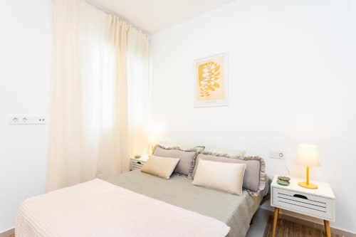 Helles Schlafzimmer in der Triana Toscal Wohnung, Santa Cruz de Tenerife, mit Queensize-Bett, gelben Kunstwerken und modernem Weiß