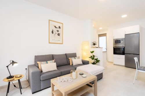 Modernes Apartment mit offener Raumgestaltung in Santa Cruz de Tenerife, grauem Sofa, Holzcouchtisch und ausgestatteter Küche