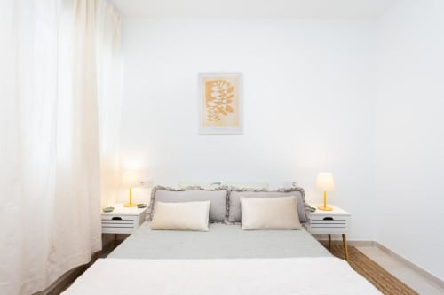 Helles Schlafzimmer im Apartment Triana Toscal, Santa Cruz de Tenerife, mit Queensize-Bett, weißen Nachttischen und warmen Lampen