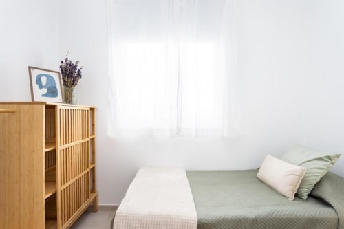 Helles Schlafzimmer im Apartment Triana Toscal, Santa Cruz de Teneriffa, mit Holzschrank, Bett mit Kissen und großen Fenstern