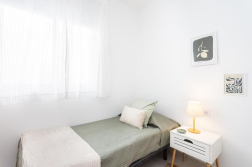 Helles Schlafzimmer im Triana Toscal Apartment in Santa Cruz de Tenerife mit Bett, weißem Nachttisch, Lampe und Wandkunst