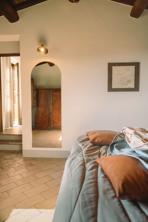 Camera da letto all'Agriturismo Il Serraglio di Montepulciano con letto, portale ad arco e travi di legno rustico