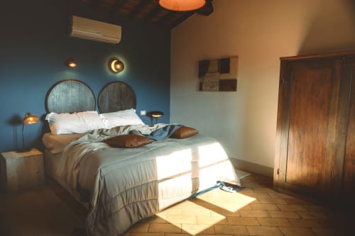 Camera luminosa all'Agriturismo Il Serraglio di Montepulciano con parete blu, testata in legno rotonda, biancheria bianca e