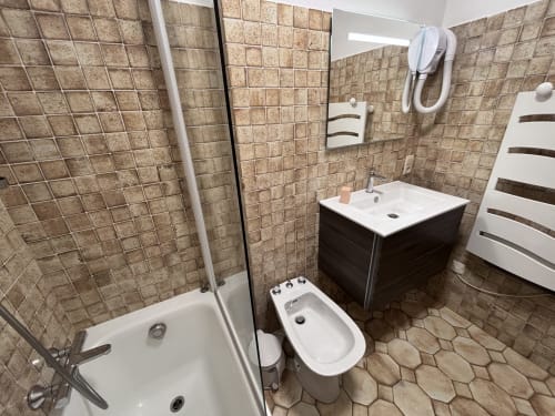Modern bathroom at Chez Francine with sink, toilet, bidet, shower, heated towel rack and beige tile walls