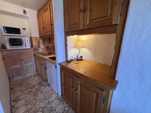 Kitchen and study nook with wooden cabinets and desk lamp in Studio Lachat apartment at Chez Francine, Notre Dame de