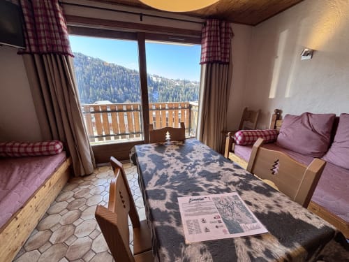 Studio apartment at Chez Francine with mountain views, twin beds with purple cushions, dining table, and snowy alpine scenery
