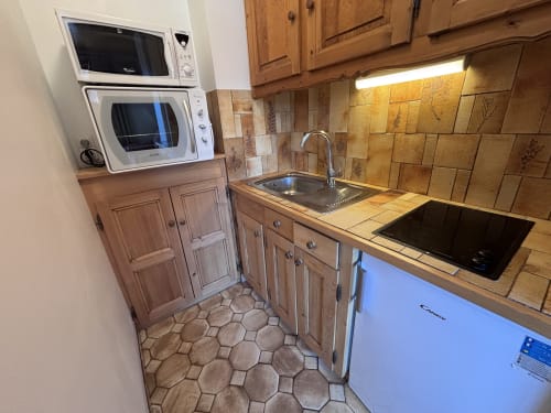 Kitchen in Studio Lachat apartment at Chez Francine, Notre Dame de Bellecombe, with wooden cabinets, tiled backsplash, and