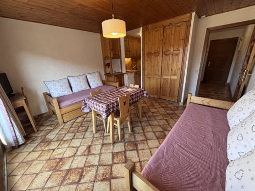 Spacious studio apartment at Chez Francine with two beds, wooden furnishings, dining table, and terracotta tiled floor in