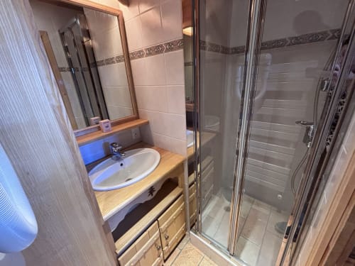 Modern bathroom with wooden vanity, round sink, mirror, and glass shower enclosure at Chez Francine apartment, Notre Dame de