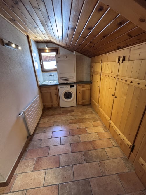 Laundry room in Chez Francine apartment, Notre Dame de Bellecombe, with washing machine, dryer, wooden cabinetry and tile