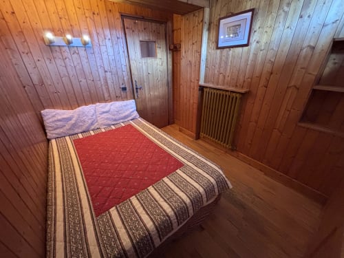 Cozy bedroom at Chez Francine apartment in Notre Dame de Bellecombe with wooden walls, red bedcover, and mountain chalet