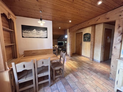 Spacious wooden apartment interior at Chez Francine with dining area, fireplace, and mountain view artwork in Notre Dame de