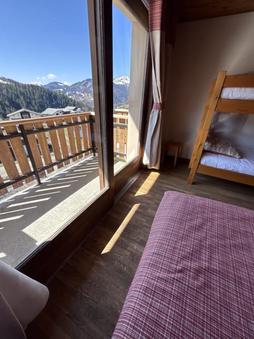 Alpine apartment bedroom with bunk bed, balcony, and snowy mountain views in Notre Dame de Bellecombe