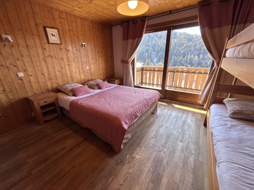Mountain-view bedroom in Chez Francine apartment with double bed, bunk bed, wooden decor and balcony overlooking Notre Dame