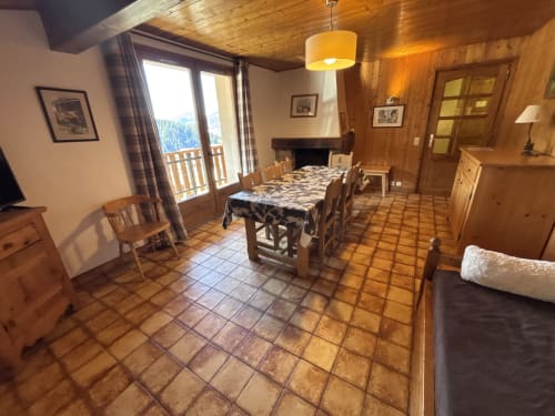 Warm wooden dining room with mountain views, fireplace, and balcony in Chez Francine apartment, Notre Dame de Bellecombe