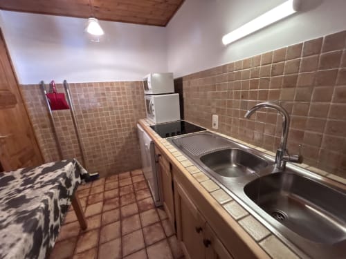 Kitchen with double sink, stove, and beige tile backsplash in Chez Francine apartment, Notre Dame de Bellecombe