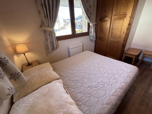 Bright bedroom with double bed, mountain view window, wooden wardrobe, and lamp at Chez Francine apartment in Notre Dame de