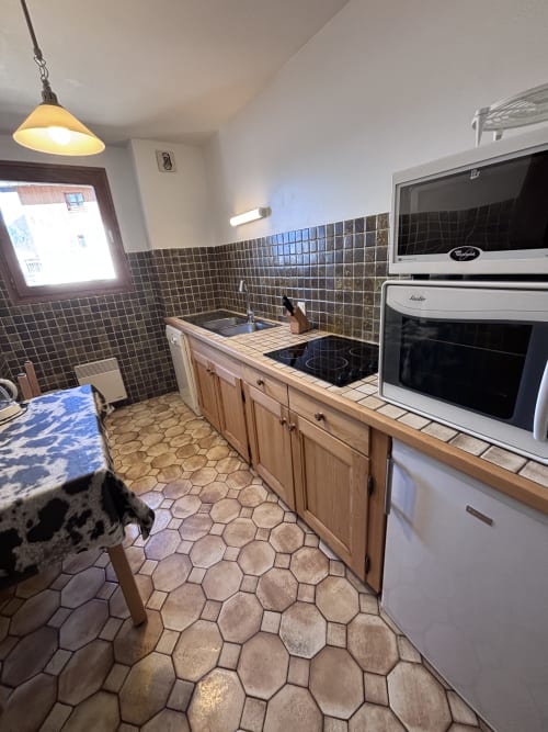 Modern kitchen in Chez Francine apartment with wooden cabinetry, black tile backsplash, stainless steel appliances, and