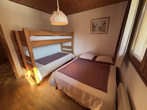 Cozy bedroom at Chez Francine with wooden bunk bed, single bed, and rustic decor in Notre Dame de Bellecombe