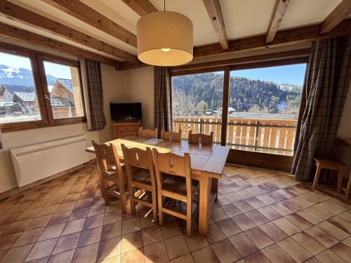 Alpine apartment dining room with mountain views, wooden beams, and balcony in Notre Dame de Bellecombe