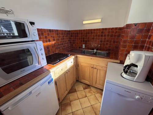 Fully equipped kitchen at Chez Francine apartment with red tile backsplash, wooden cabinets, and modern appliances