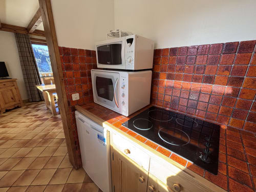Kitchen at Chez Francine in Notre Dame de Bellecombe with red tile backsplash, electric cooktop, microwave, and dishwasher
