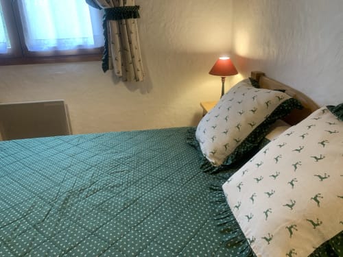 Cozy bedroom in Chez Francine apartment with twin beds, patterned pillows, lamp, and garden view in Notre Dame de Bellecombe