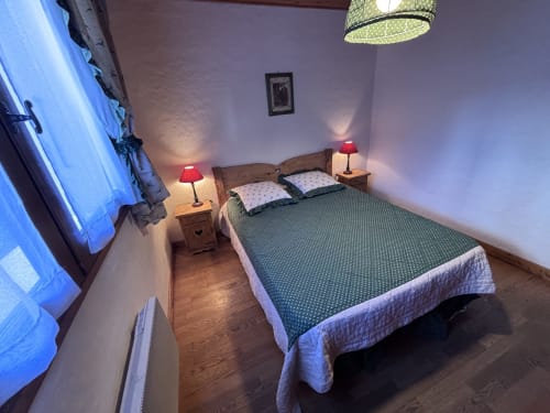 Cozy bedroom at Chez Francine apartment with double bed, red lamps, wooden nightstands, and blue neon accent lighting in