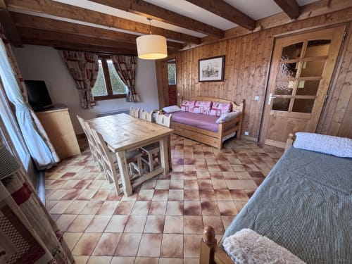 Spacious apartment interior at Chez Francine with wooden beams, dining table, sofa bed, and terracotta tile flooring in Notre