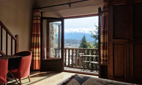 Habitación doble deluxe con balcón en Hotel Mas D'En Roqueta, con vistas a la montaña y puertas de madera hacia la terraza
