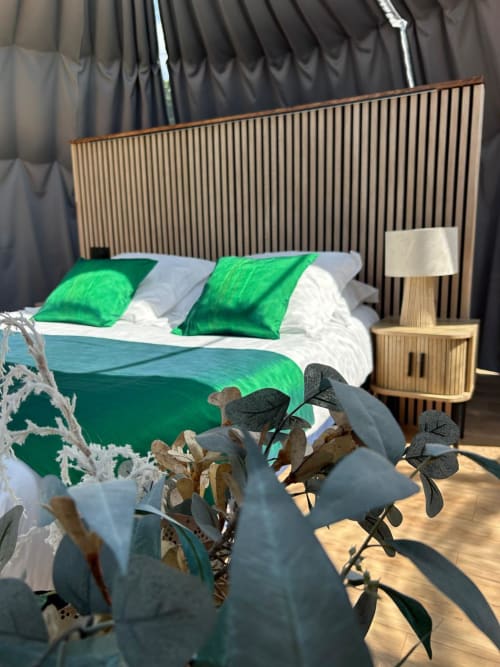 Chambre Bulle Émeraude de l'hôtel Bubble Jade avec coussins en velours vert, tête de lit en bois, vue sur le jardin et plantes en pot