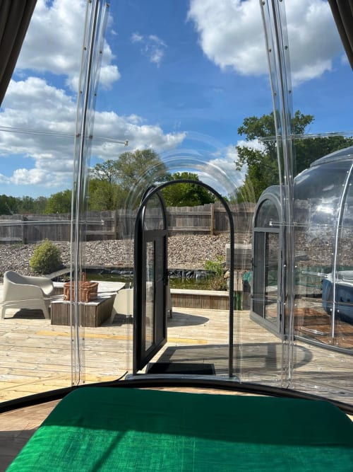 Vue intérieure de la chambre bulle transparente à l'hôtel Bubble Jade à Bazouges la Pérouse, France, avec vue sur le jardin et l'extérieur