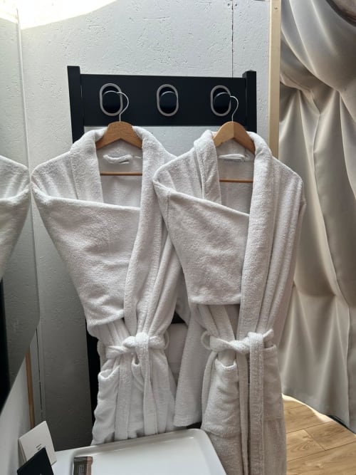 Deux peignoirs blancs suspendus à des cintres en bois à l'hôtel Bubble Jade à Bazouges la Pérouse