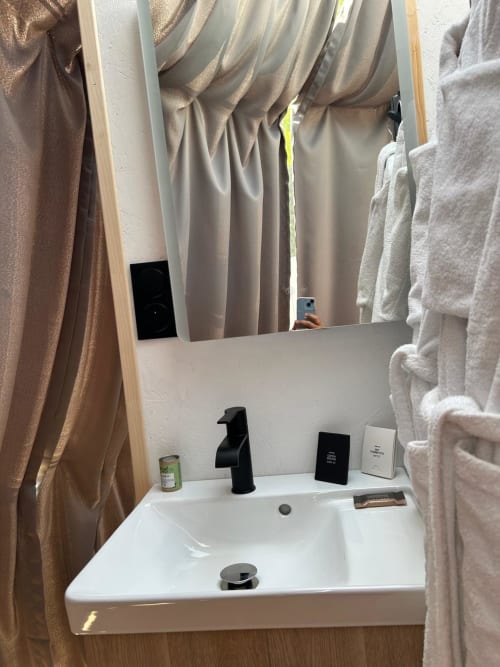 Lavabo de salle de bains avec robinetterie noire à l'hôtel Bubble Jade à Bazouges la Pérouse, France