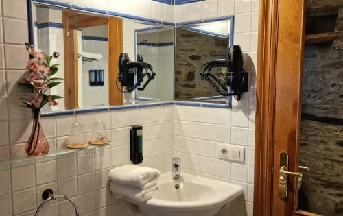 Baño moderno con azulejos tipo metro blancos, espejo grande y flores rosas en Hotel Mas D'En Roqueta, España