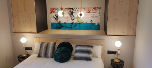 Dormitorio de casa rural moderna con cabecero de madera, cojines decorativos, lámparas de mesita y cuadro floral abstracto en Hotel Mas