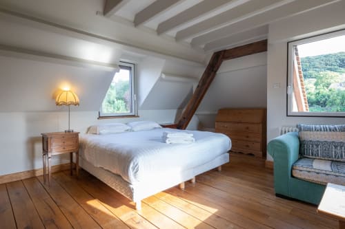 Chambre lumineuse sous les toits à la villa La Girelle à Honfleur avec poutres apparentes, vue sur mer et mobilier rustique
