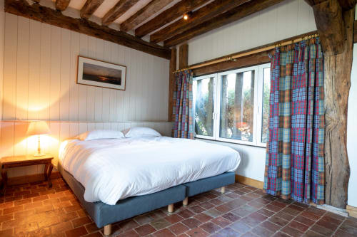 Chambre avec vue mer à La Girelle, Honfleur : poutres apparentes, rideaux à carreaux, sol en tomettes
